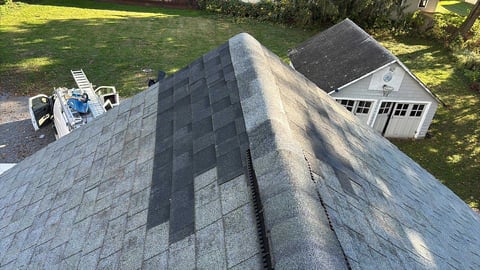 Aerial view of asphalt shingle roof with equipment and shed visible in background