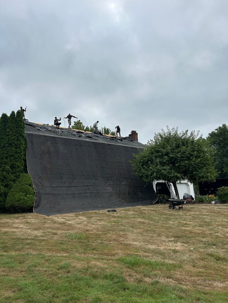 Large wooden ship structure tilted at angle in grassy field with crew members on top and support vehicle nearby