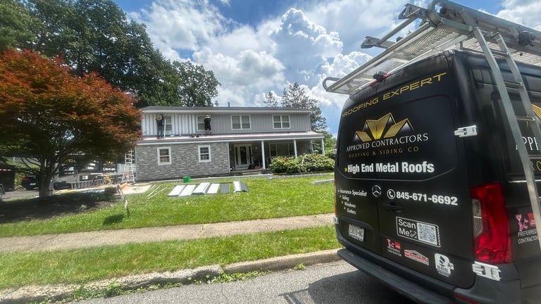 Service vehicle parked on residential street in front of gray and white two-story house with manicured lawn