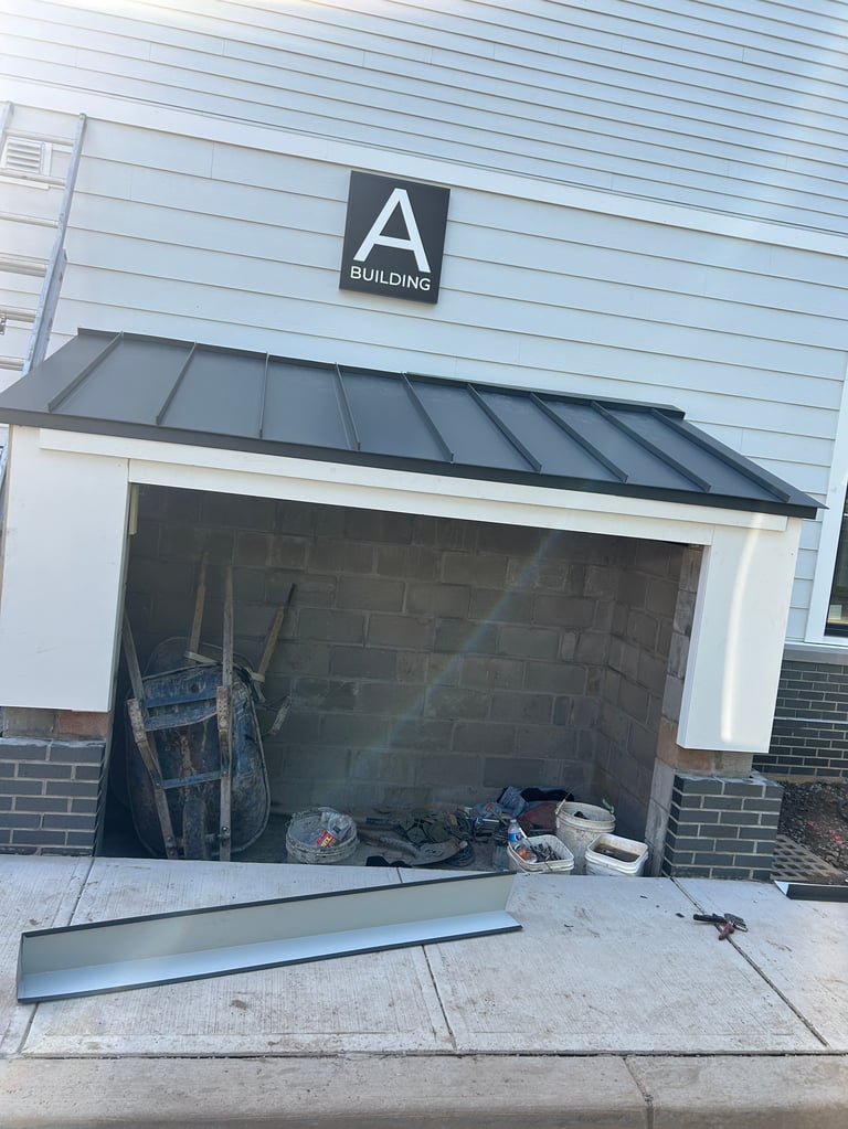 Exterior of Building A with open garage door revealing construction materials and equipment stored inside